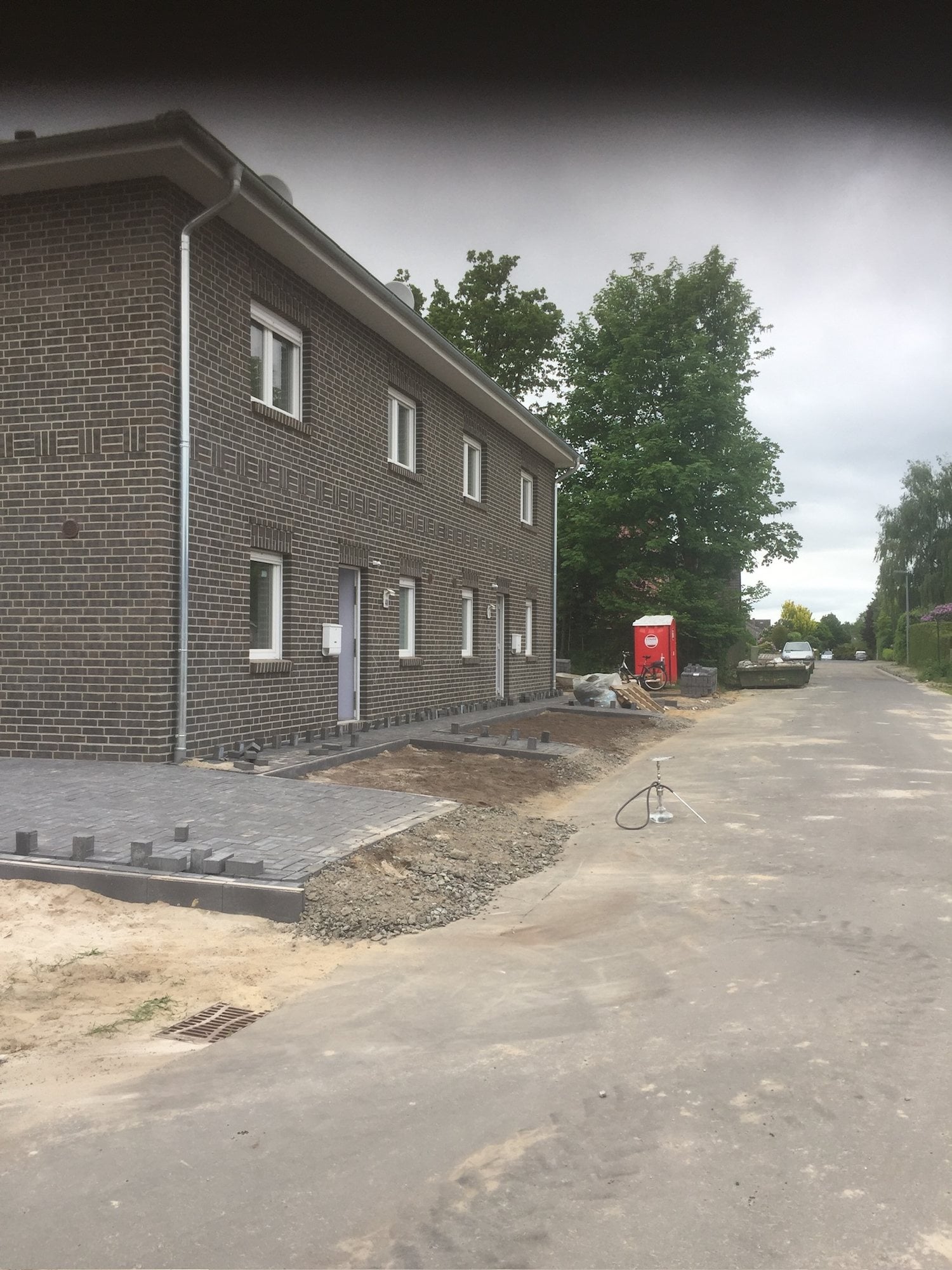 Fertiges Doppelhaus mit dunkler Klinkerfassade und Pflasterfläche
